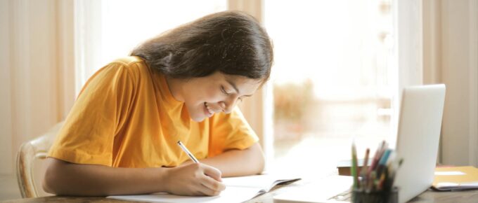 woman in yellow shirt writing on white paper